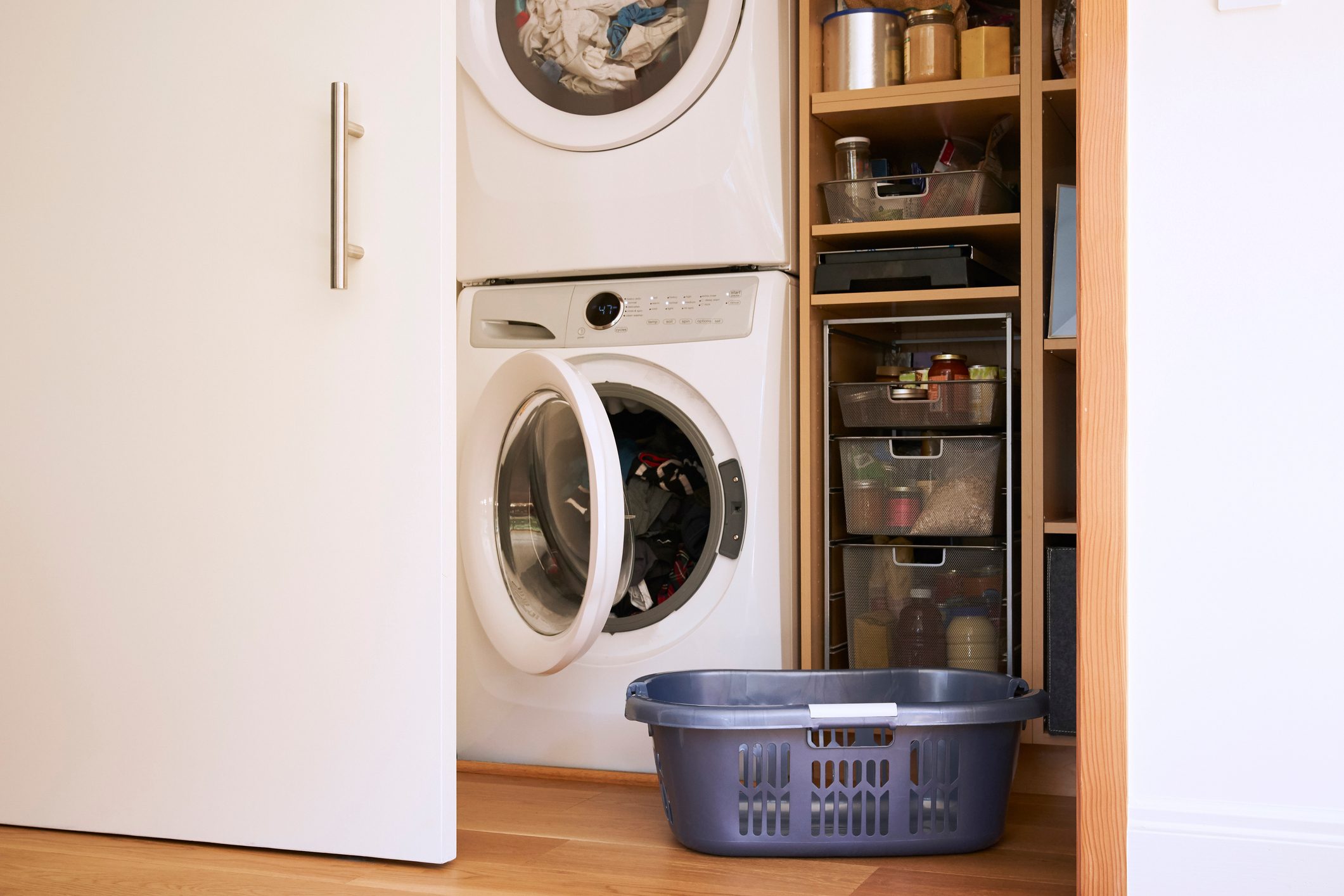 At home still life of empty laundry basket with full washing machine and dryer in the background