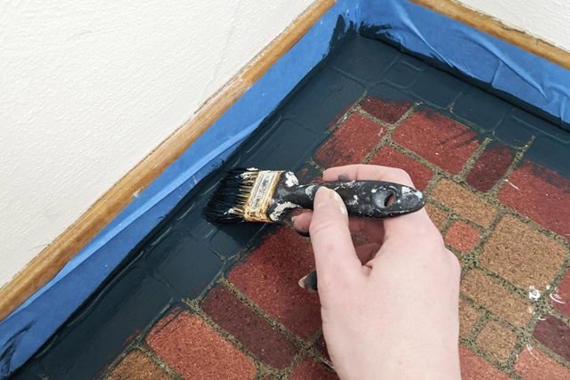 A hand can be seen painting base coat on vinyl floor.
