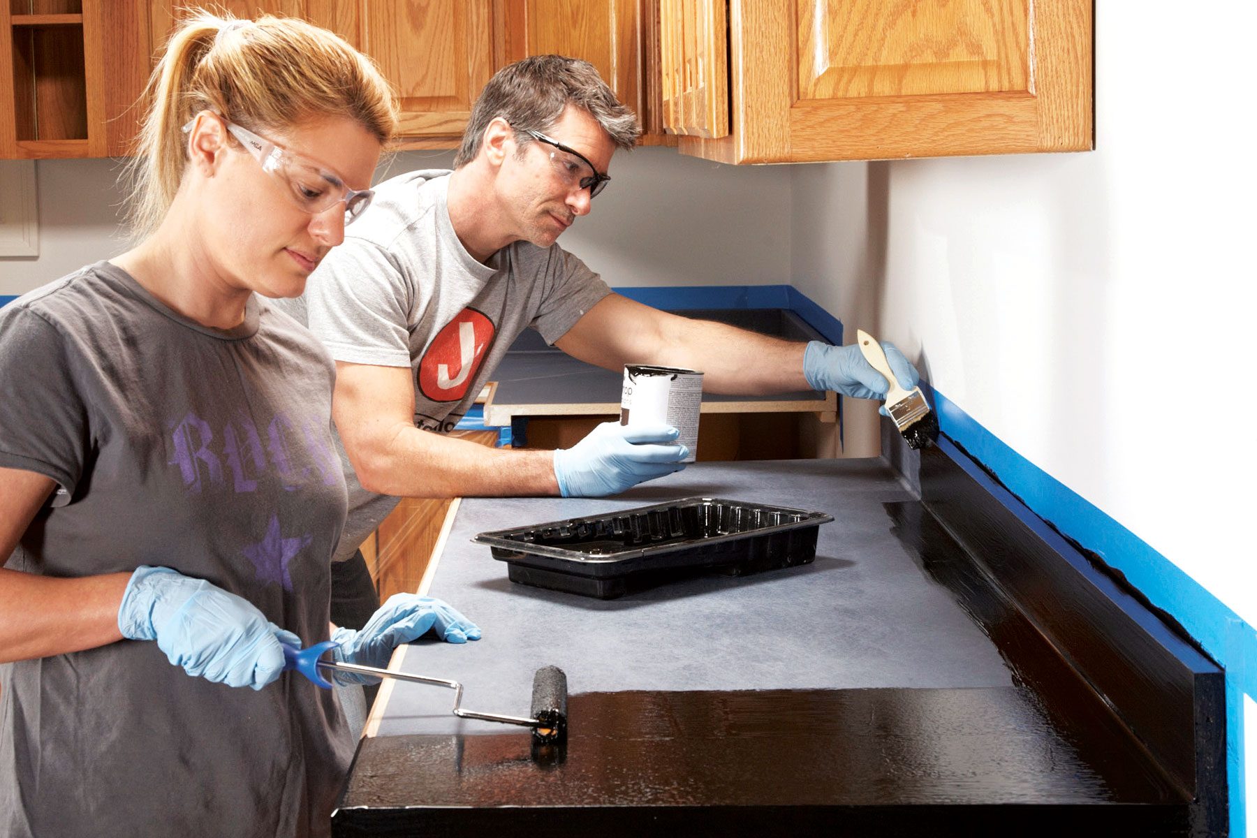 People applying base coat of paint to countertop surface.