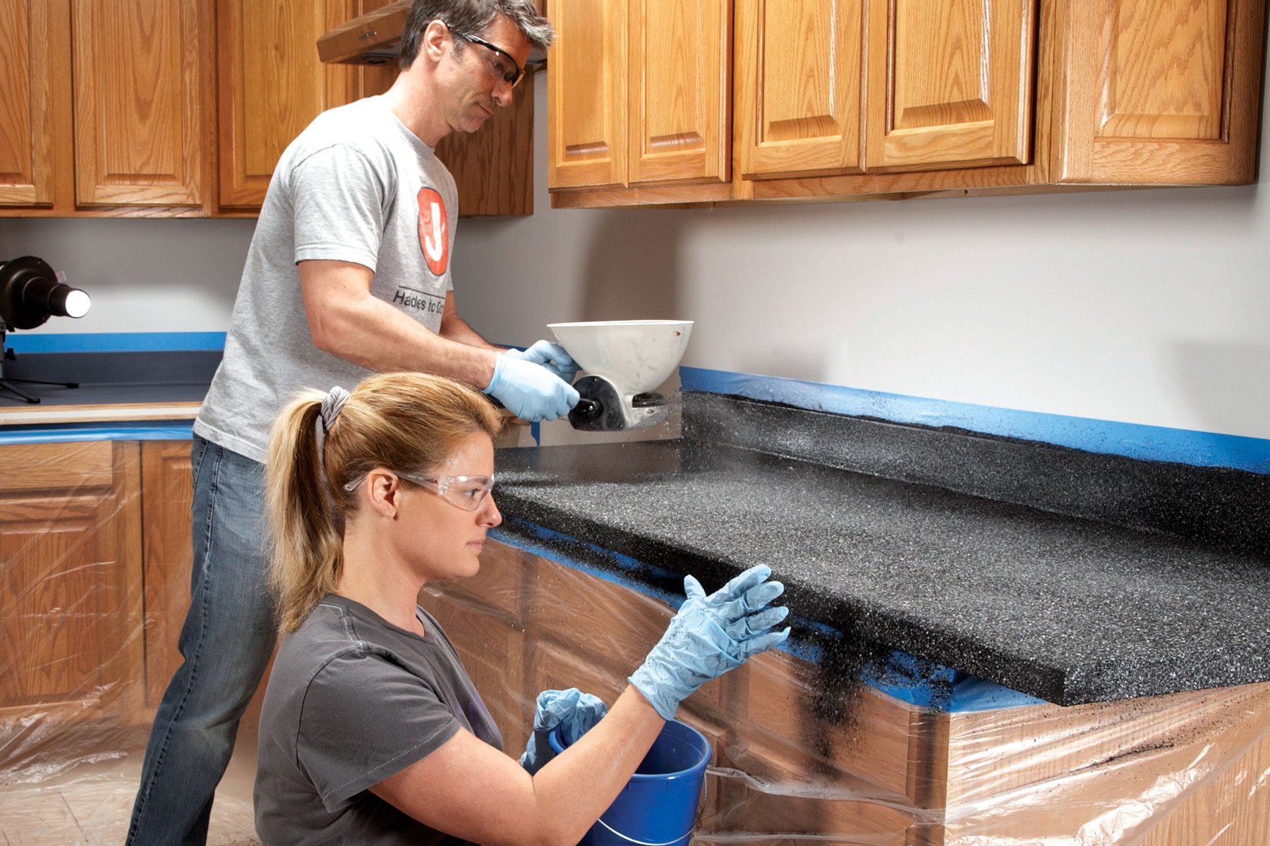 Two people applying decorative chips to countertop surface.