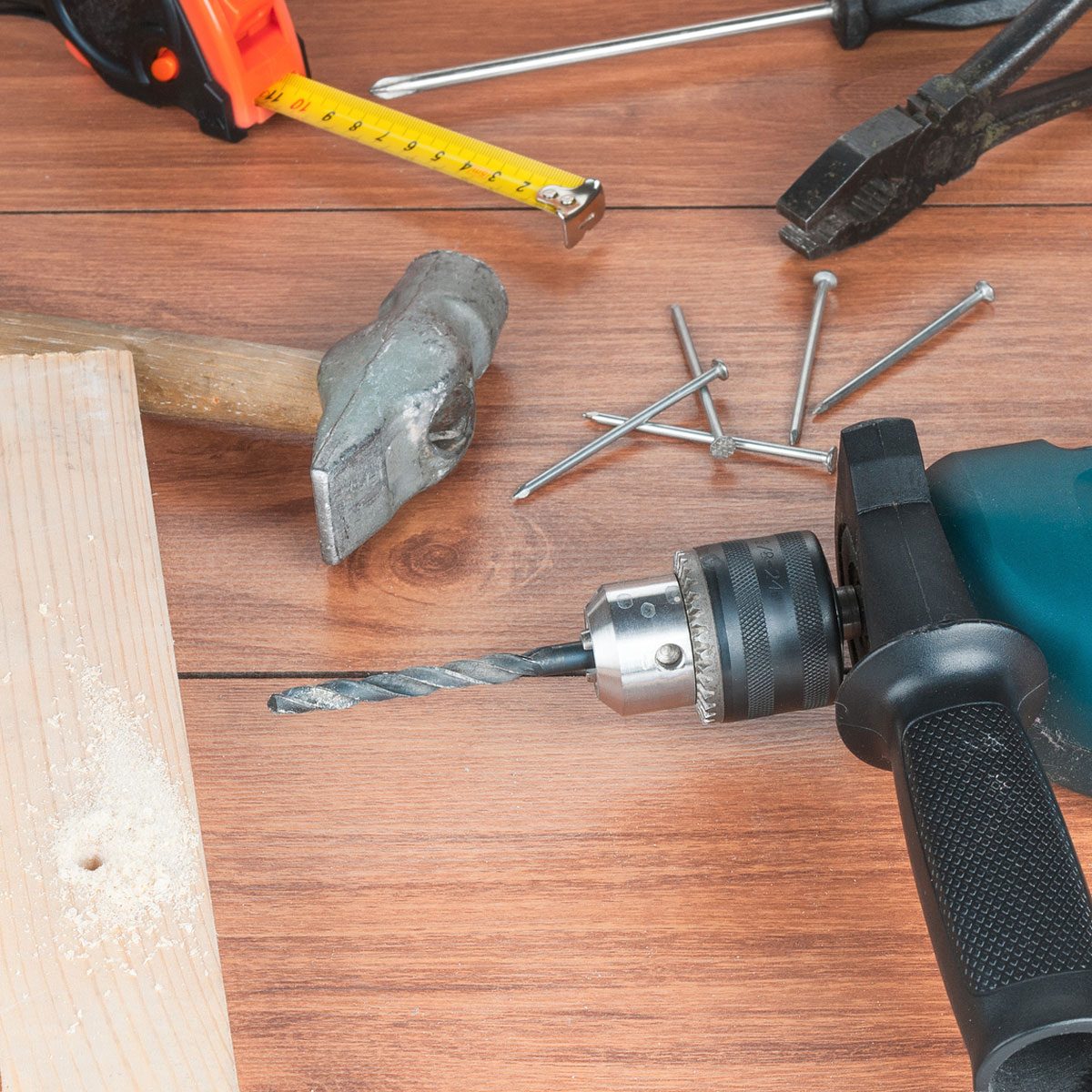 piece of wood with hole, drill, nails, pliers and measuring tape