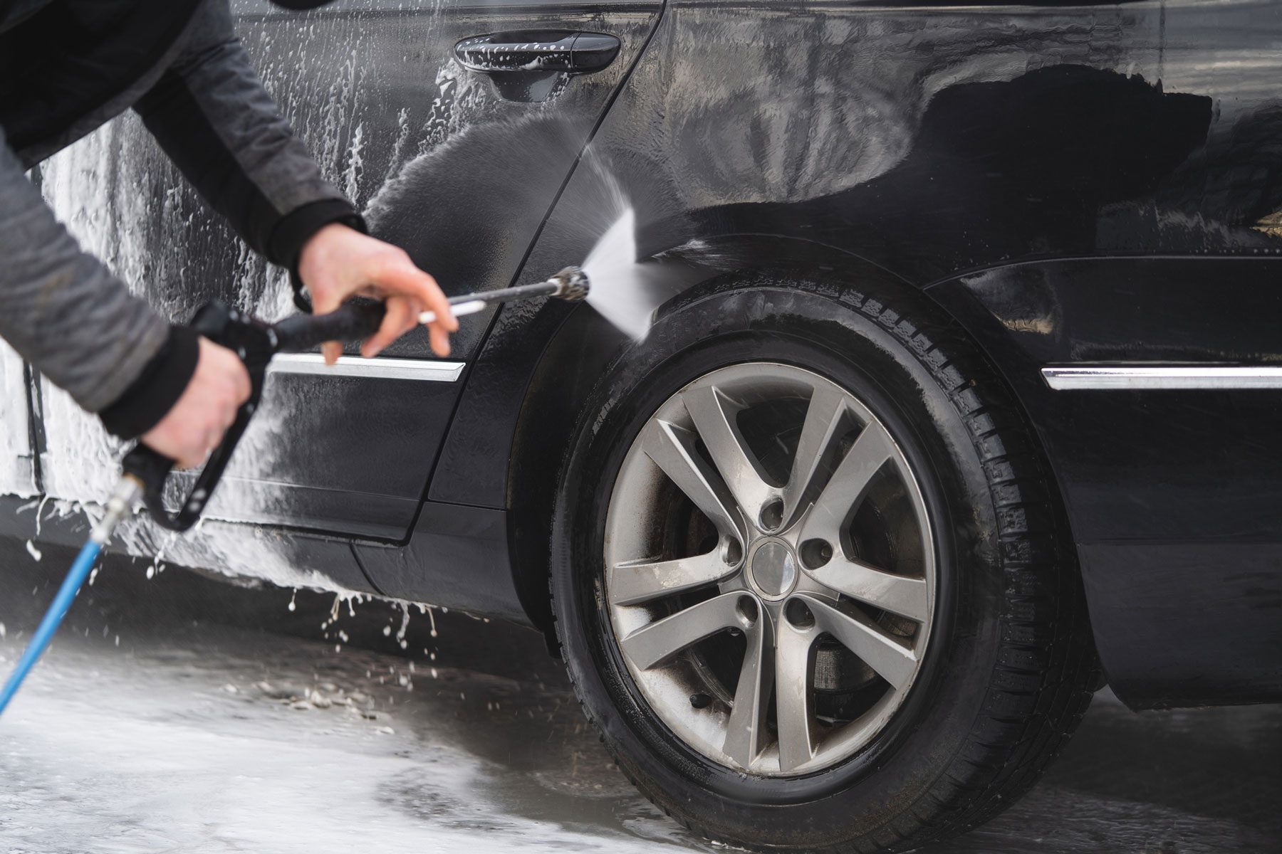 the car at the car wash is covered with foam, wash under pressure with a stream of water