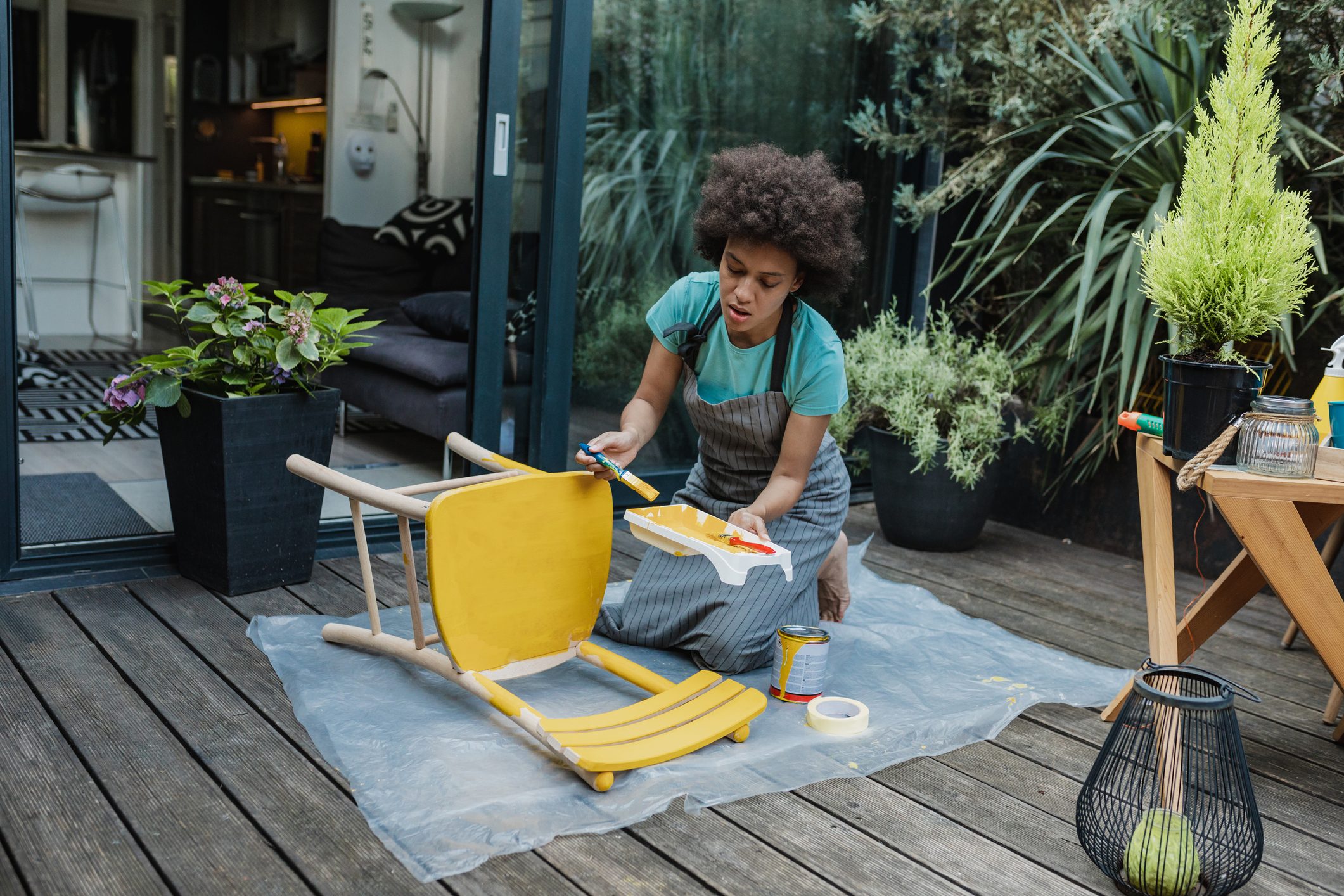 Woman is coloring an old chair at home