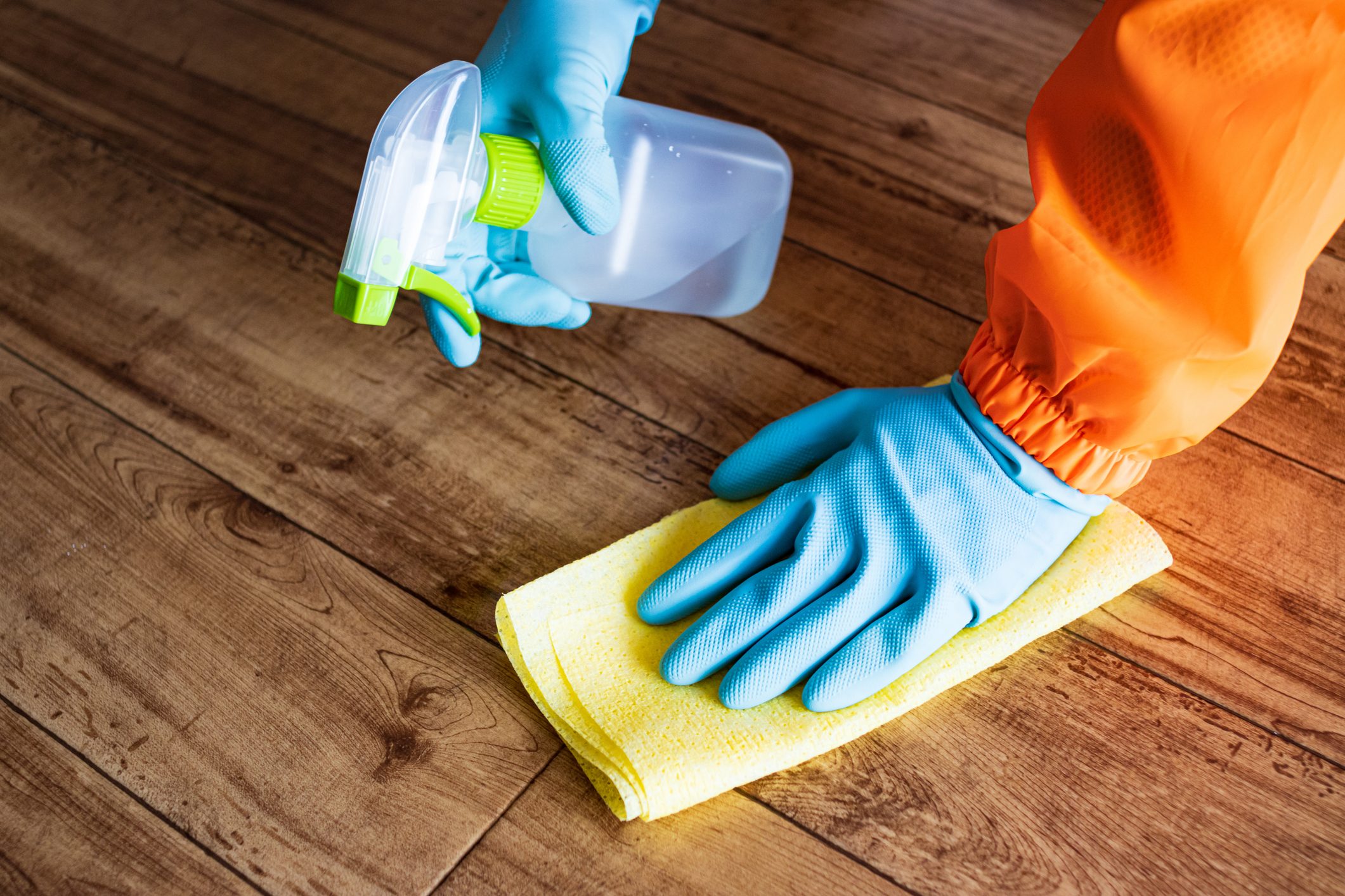 Person cleaning floor with disinfectant spray