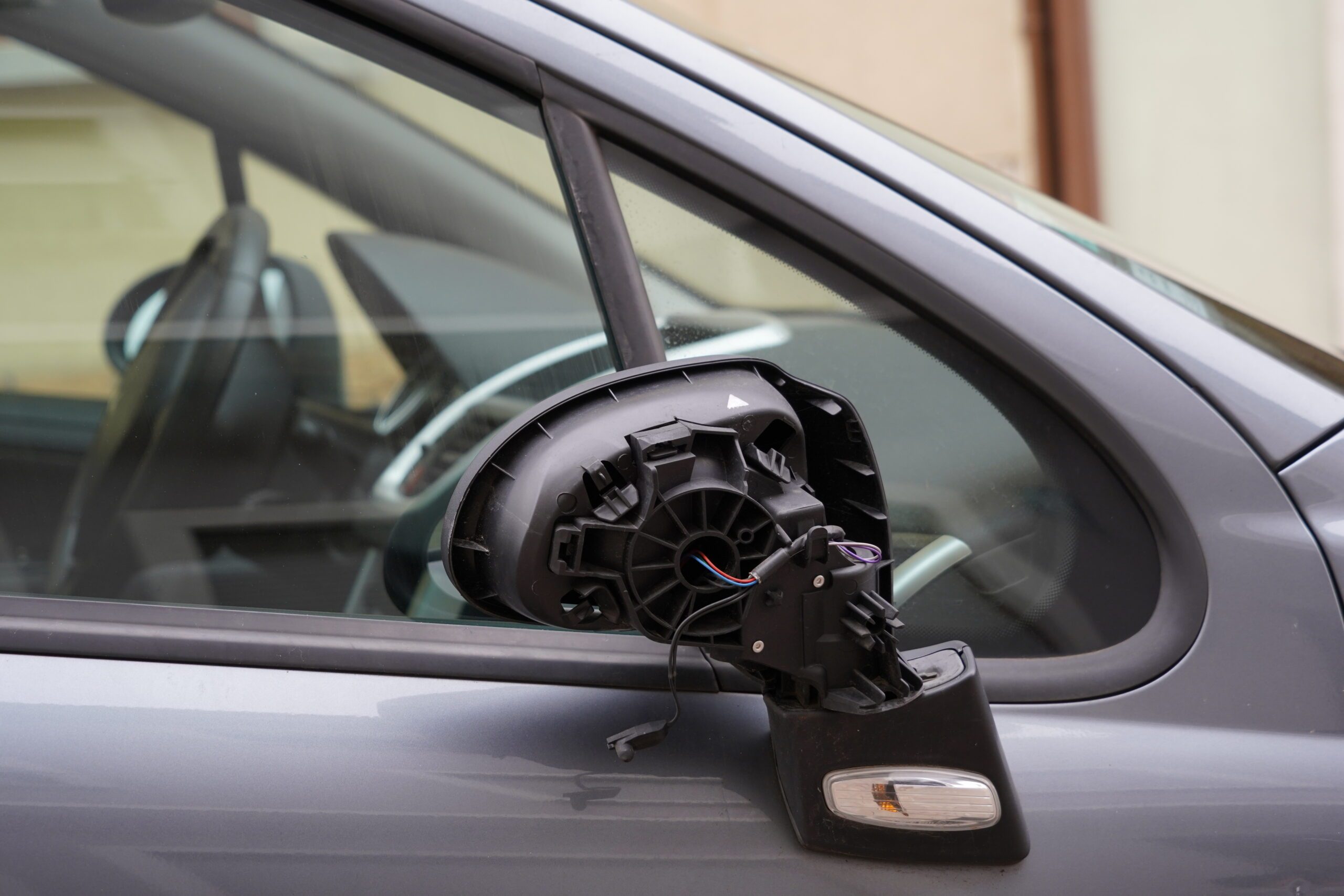 Close up view on broken adjustable door back mirror or wing mirror made from black plastic.