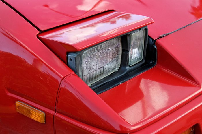 Pop-up headlight detail of red vintage car