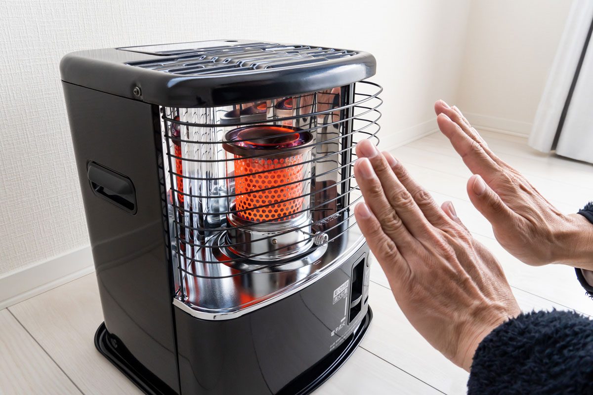 man warming hands in front of heater