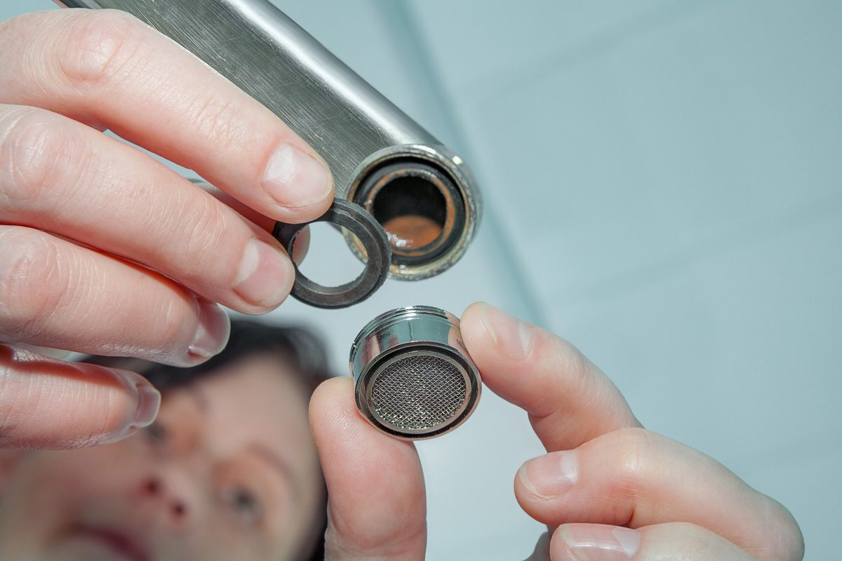 woman inspecting faucet aerator