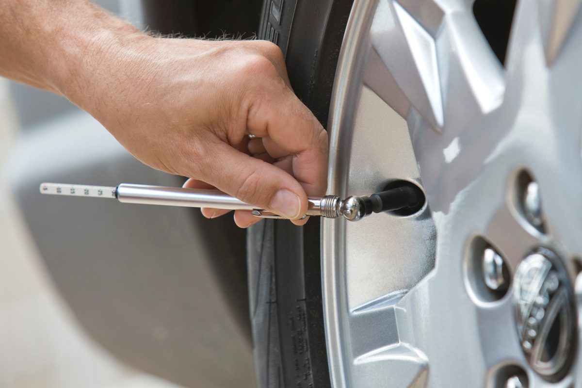 man checking car tire pressure