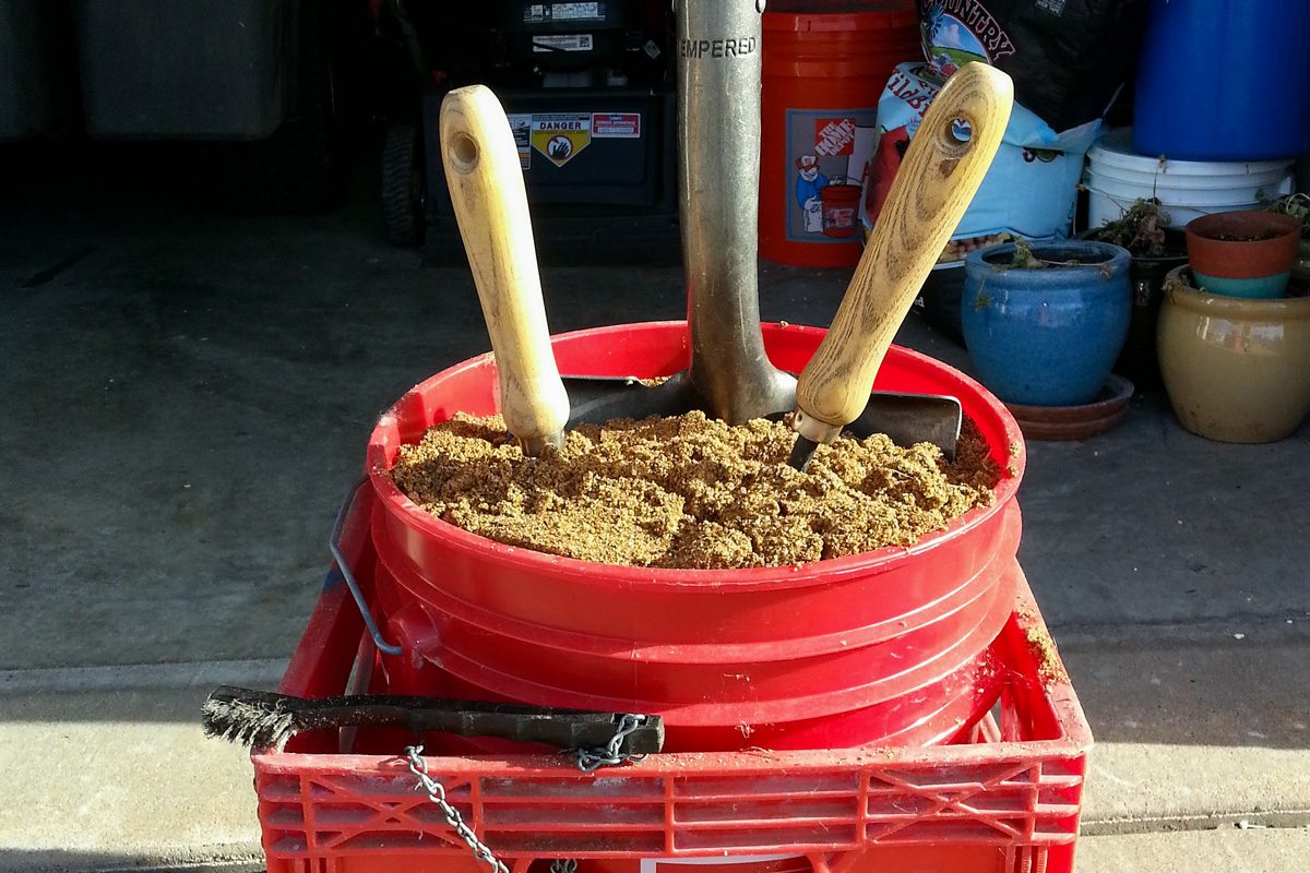 gardening tools in dirt inside a bucket