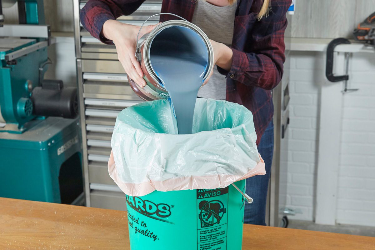 paint being poured into a bucket lined with garbage bag