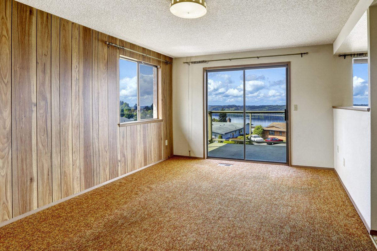 Empty room with wood plank paneled wall and carpet floor