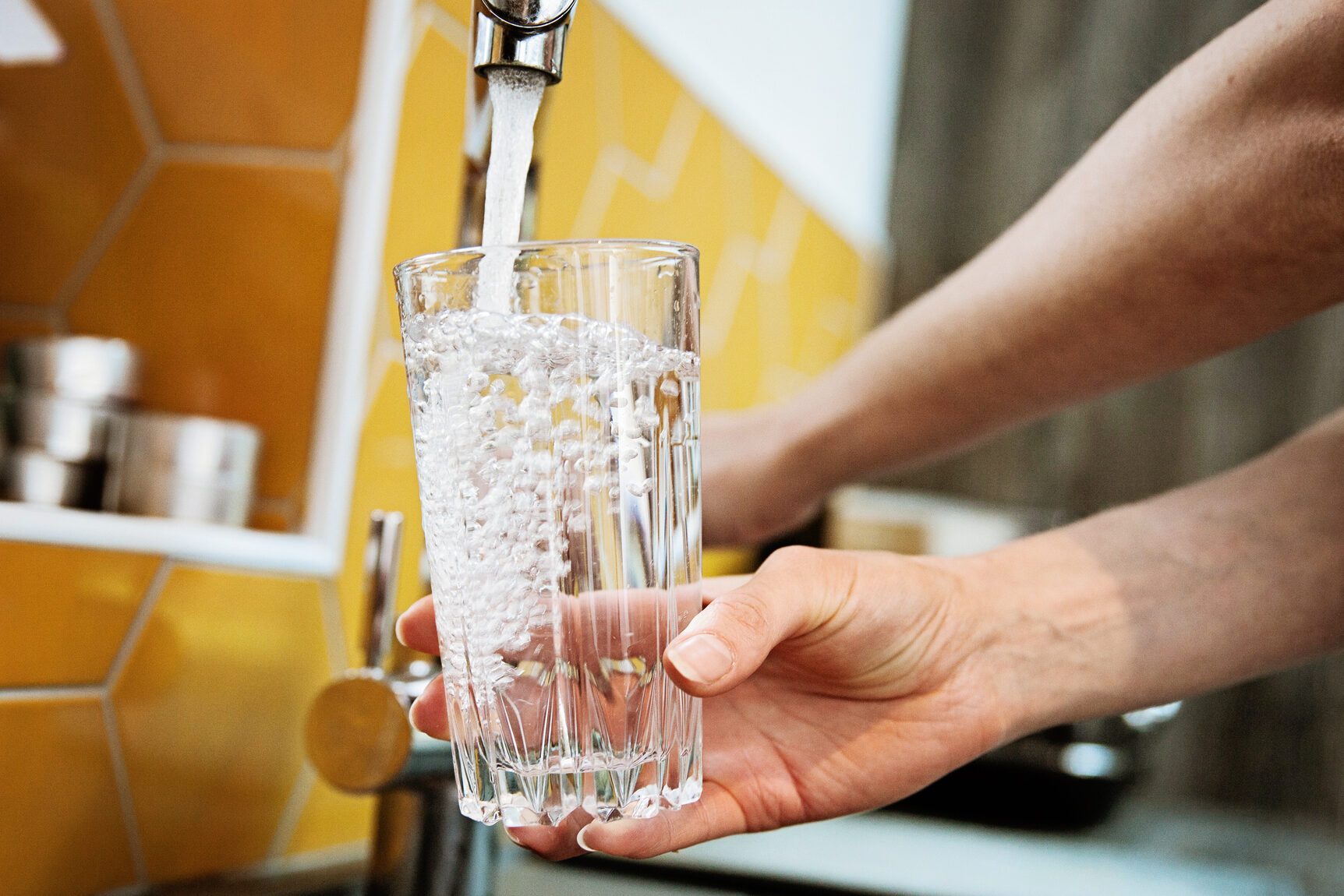 Woman filling a glass with water right from the tap