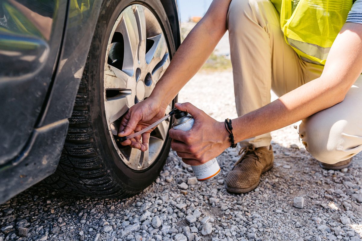 man using tire spray on his care tire