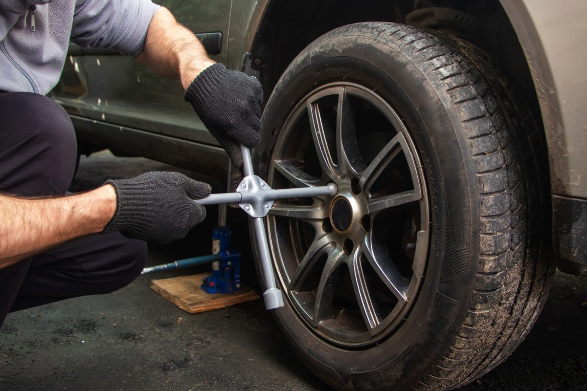 man using wrench on tire