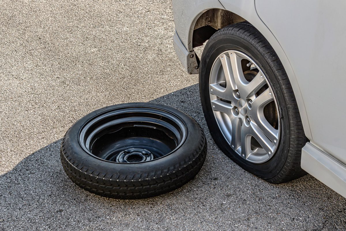 flat tire with spare next to it on road