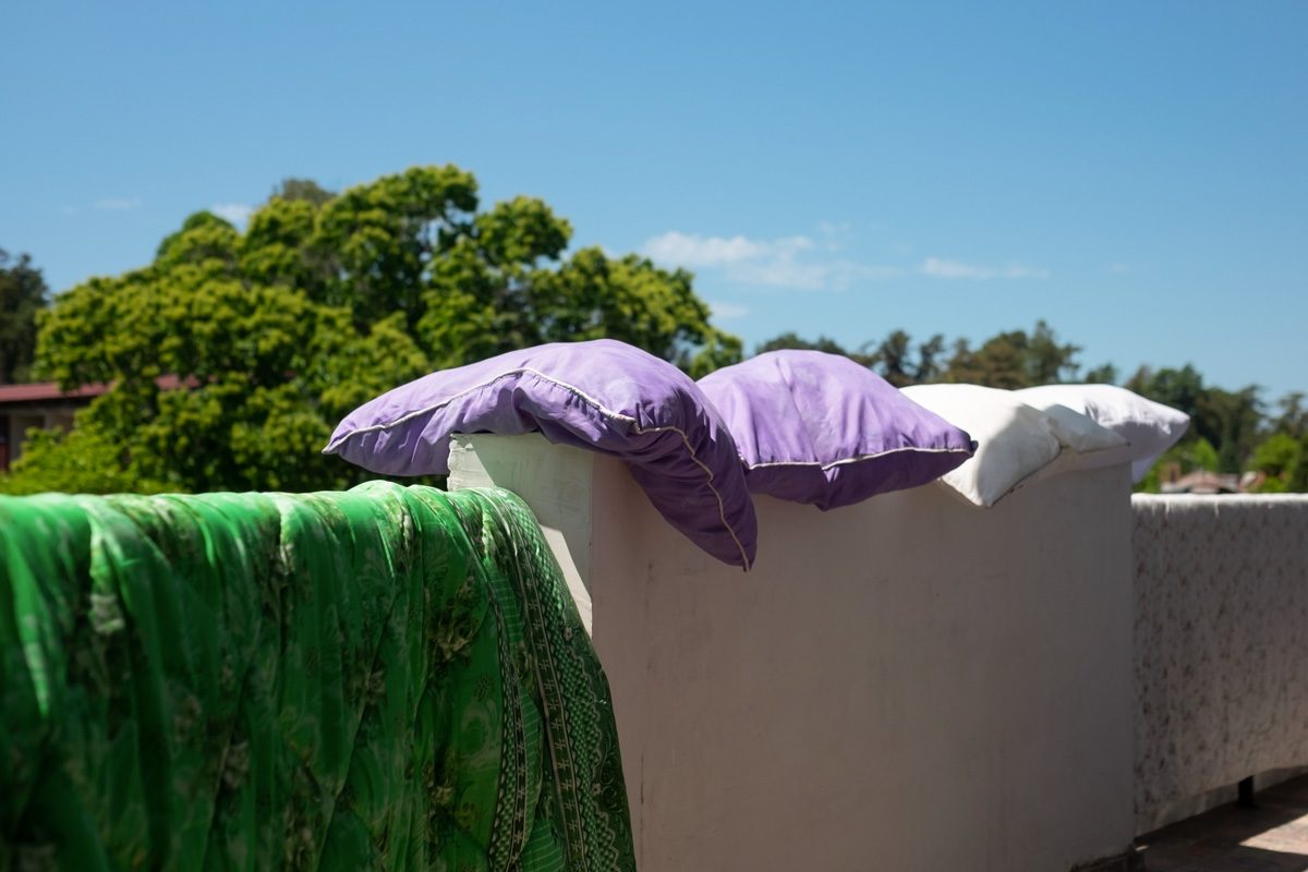 pillows and blanket drying in the sun on a wall