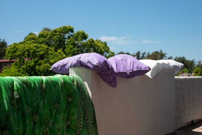 pillows and blanket drying in the sun on a wall