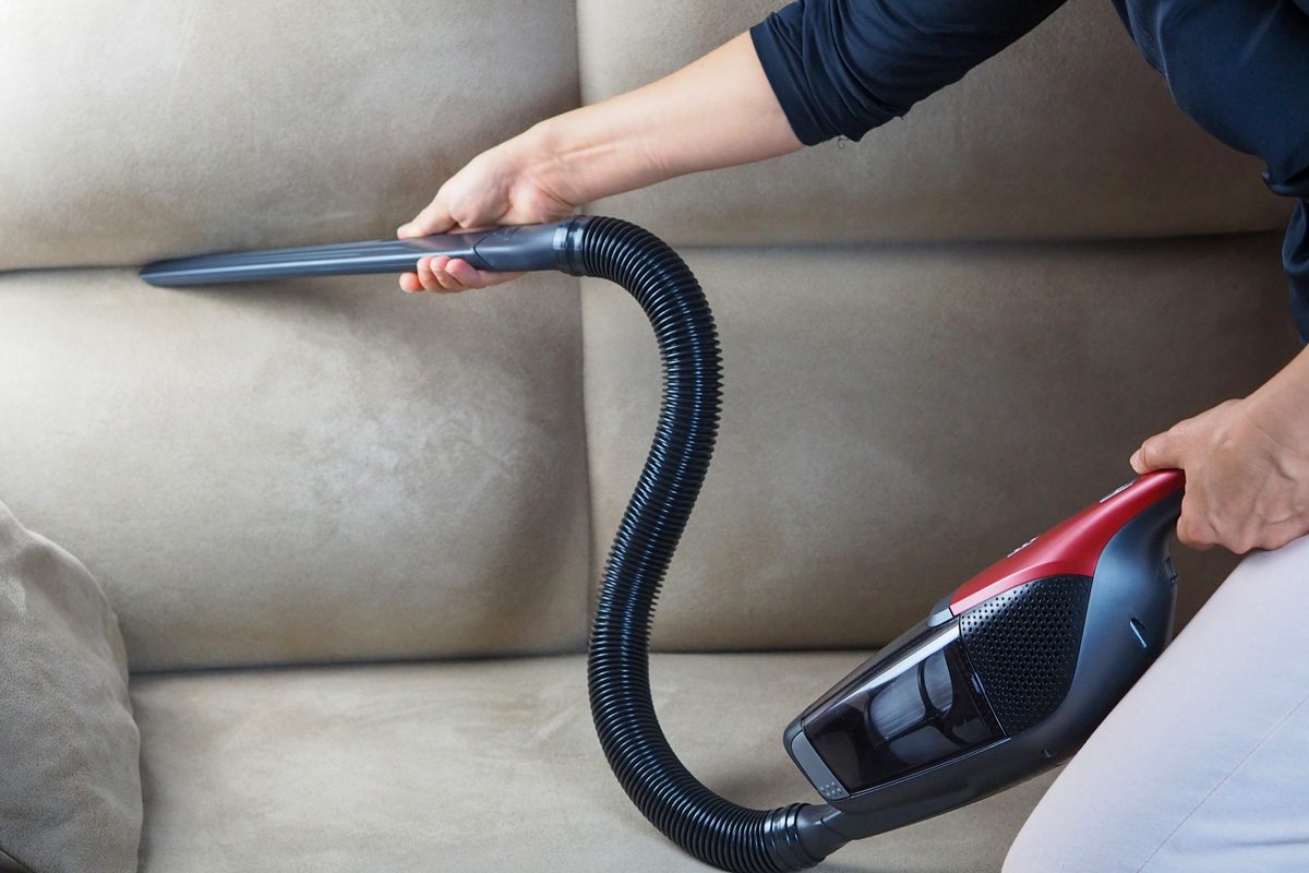 woman vacuuming a sofa