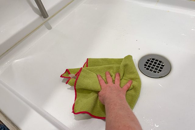 wiping bathroom surface with microfiber cloth