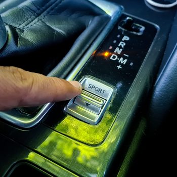 Driver's hand pressing sport mode button in luxury car