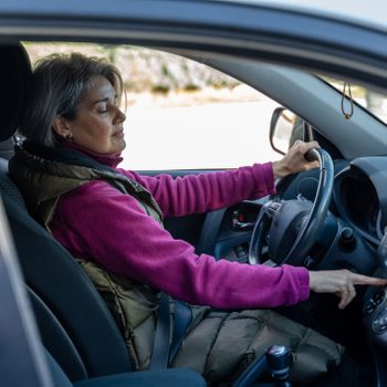 woman adjusting car temperature while driving