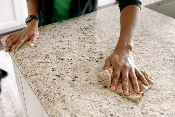 woman wiping granite kitchen counter