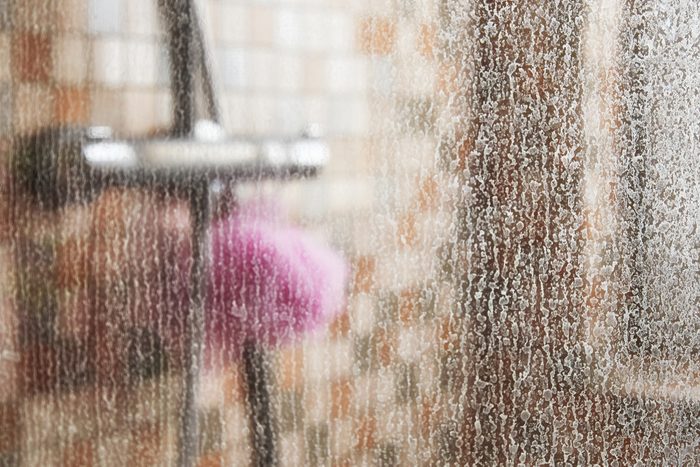 glass of shower cabin covered in limescale